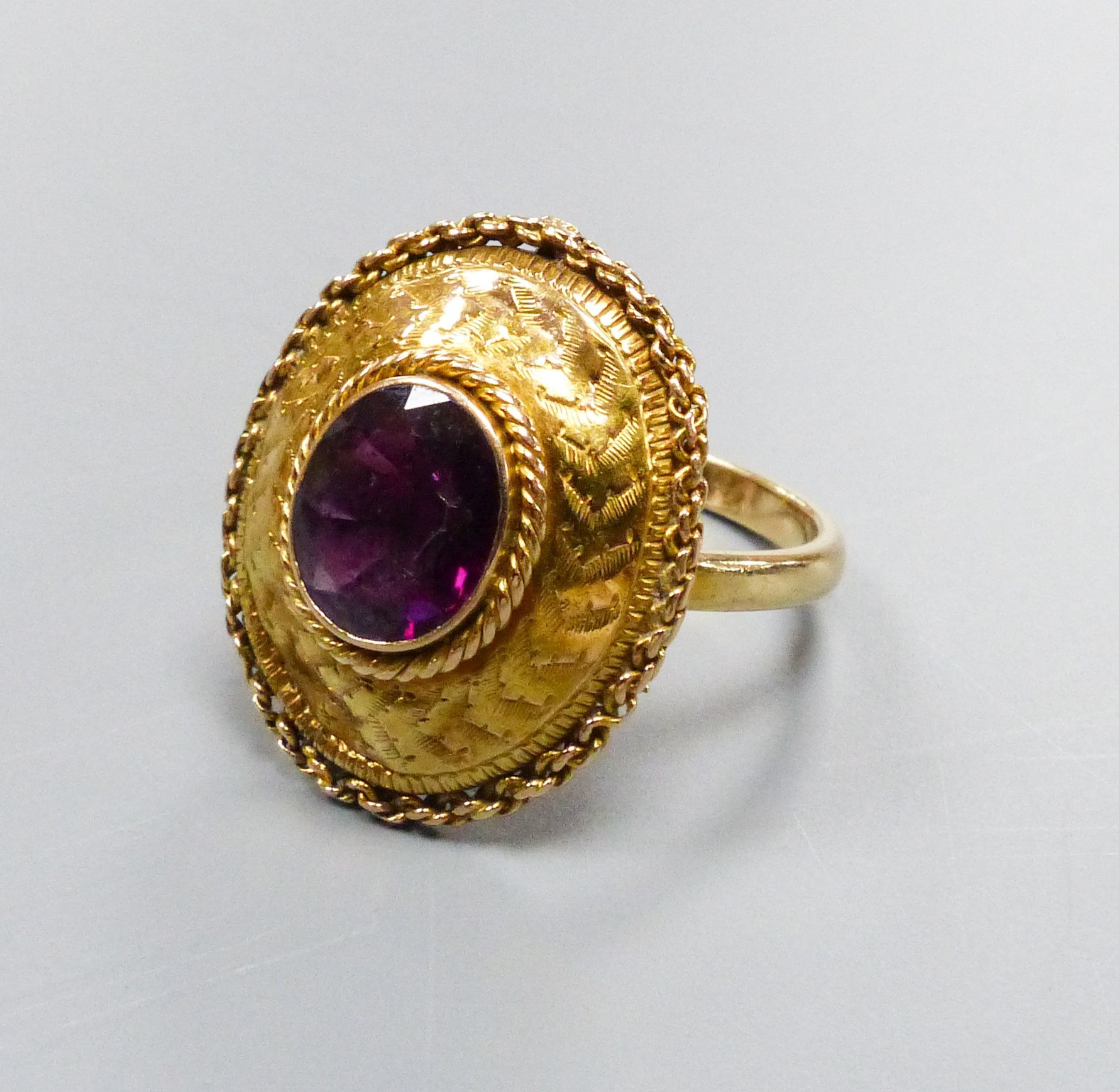 A 19th century engraved yellow metal and garnet set oval dress ring, with rope twist border (ring head loose), size N, gross weight 4.4 grams.